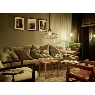 Gemütliches Wohnzimmer mit beige Sofa, dekorativen Kissen, hölzernem Couchtisch, Pendelleuchten und gerahmten Bildern an der Wand.