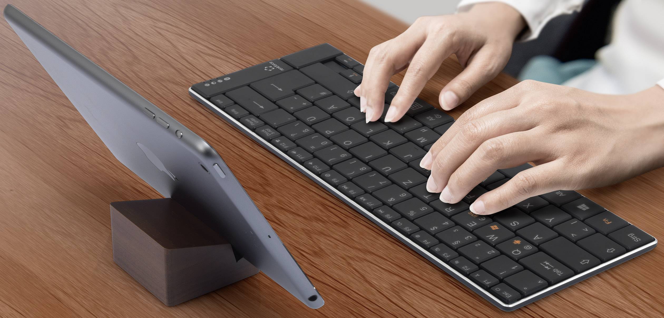 Eine Person tippt auf einer kabellosen Tastatur, die mit einem Tablet verbunden ist, das auf einem Tisch steht.