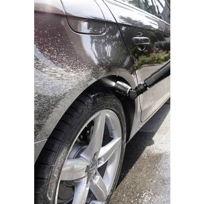 Auto wird mit Hochdruckreiniger am Rad sauber gemacht. Wassertropfen und Schaum sind auf dem Reifen und der Karosserie sichtbar.