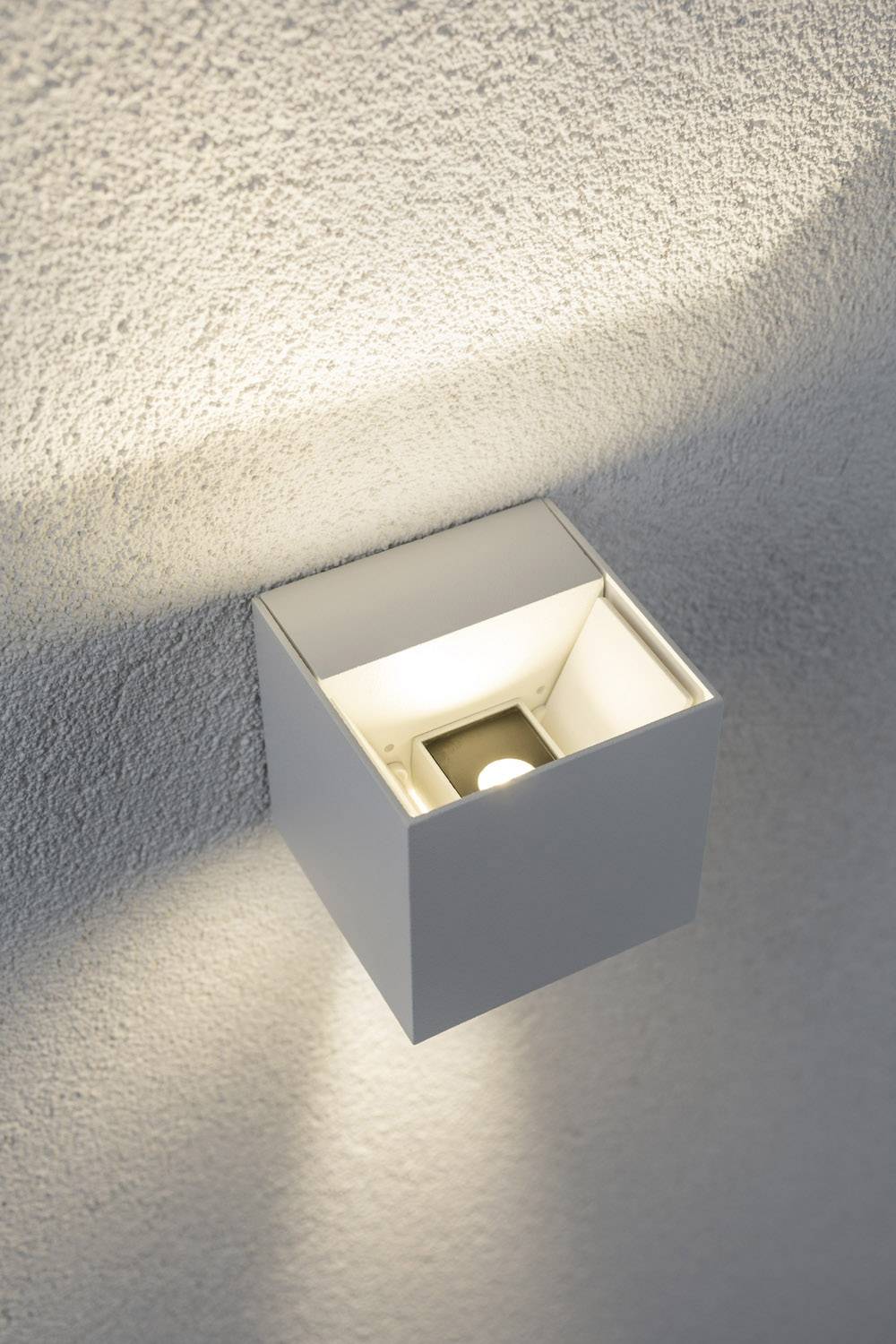Wandleuchte mit modernem, quadratischem Design spendet sanftes, indirektes Licht an einer strukturierten Wandoberfläche.