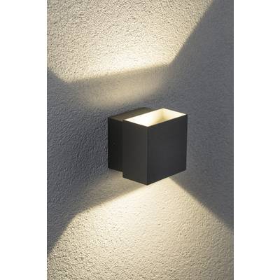 Eine moderne Wandleuchte mit rechteckigem Design wirft diffuses Licht nach oben und unten auf eine strukturierte Wand.