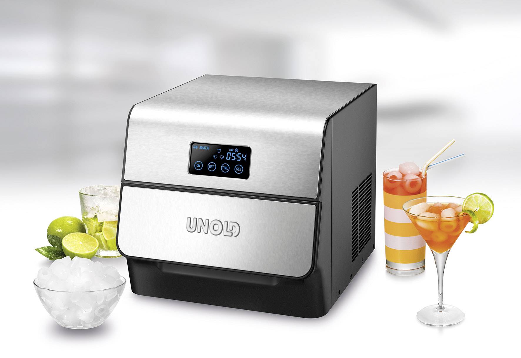 Ein moderner Eiswürfelbereiter mit digitalem Display, umgeben von Getränken mit Eis, Limetten und Orangenscheiben, auf hellem Untergrund.