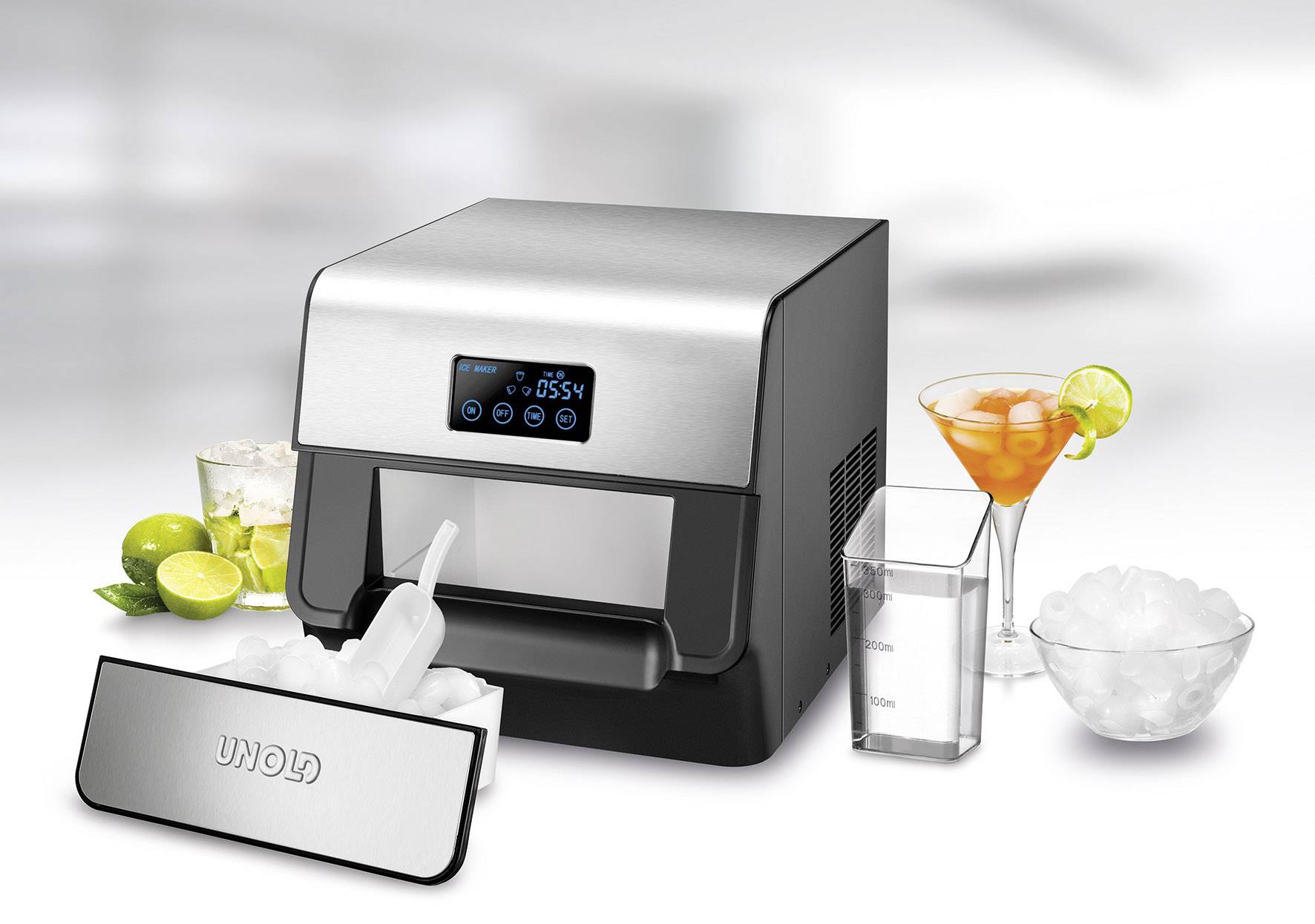 Eiswürfelmaschine auf Tisch, umgeben von Cocktailgläsern, Limetten und Eiswürfelbehälter. Display zeigt 'CLEAR ICE'.