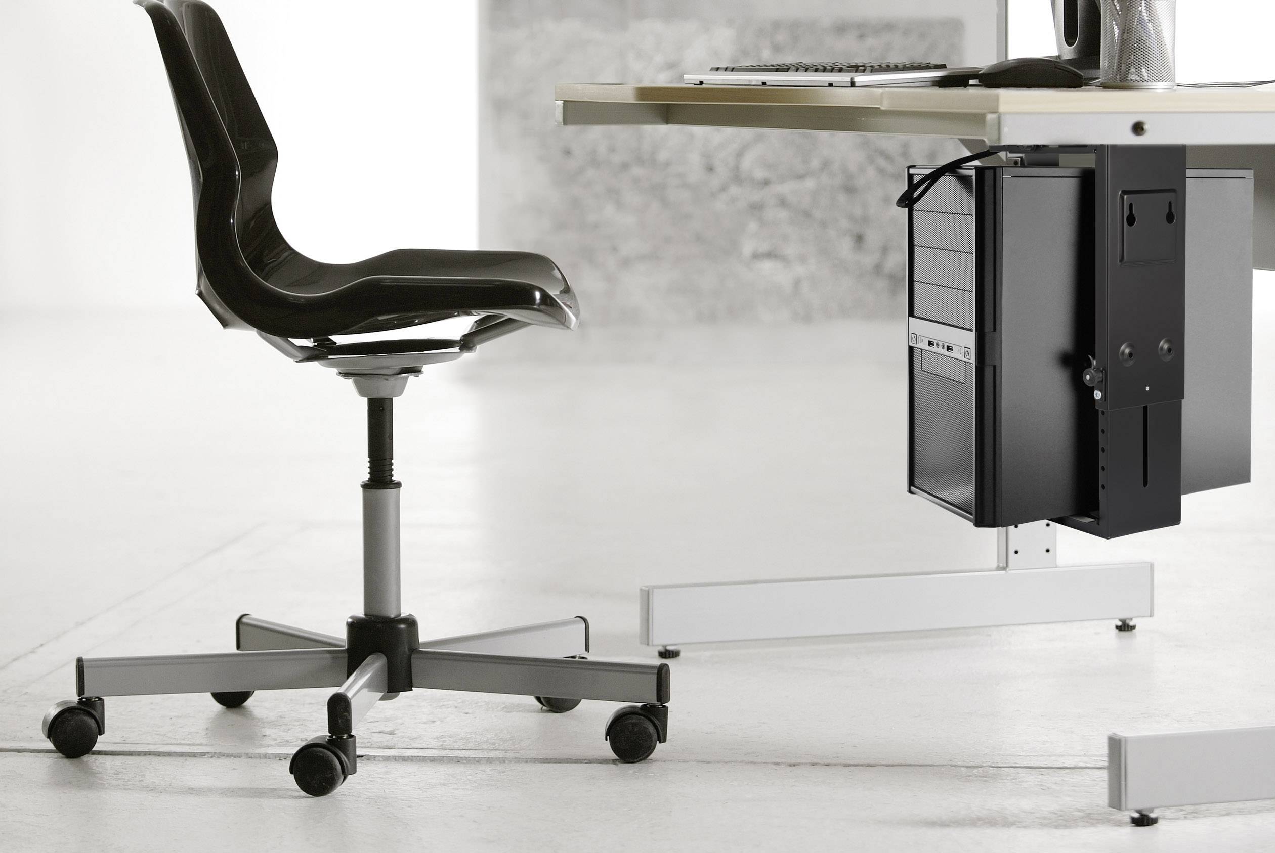 Ein moderner Bürostuhl mit Rädern steht neben einem Schreibtisch, auf dem ein Computer und Zubehör platziert sind.