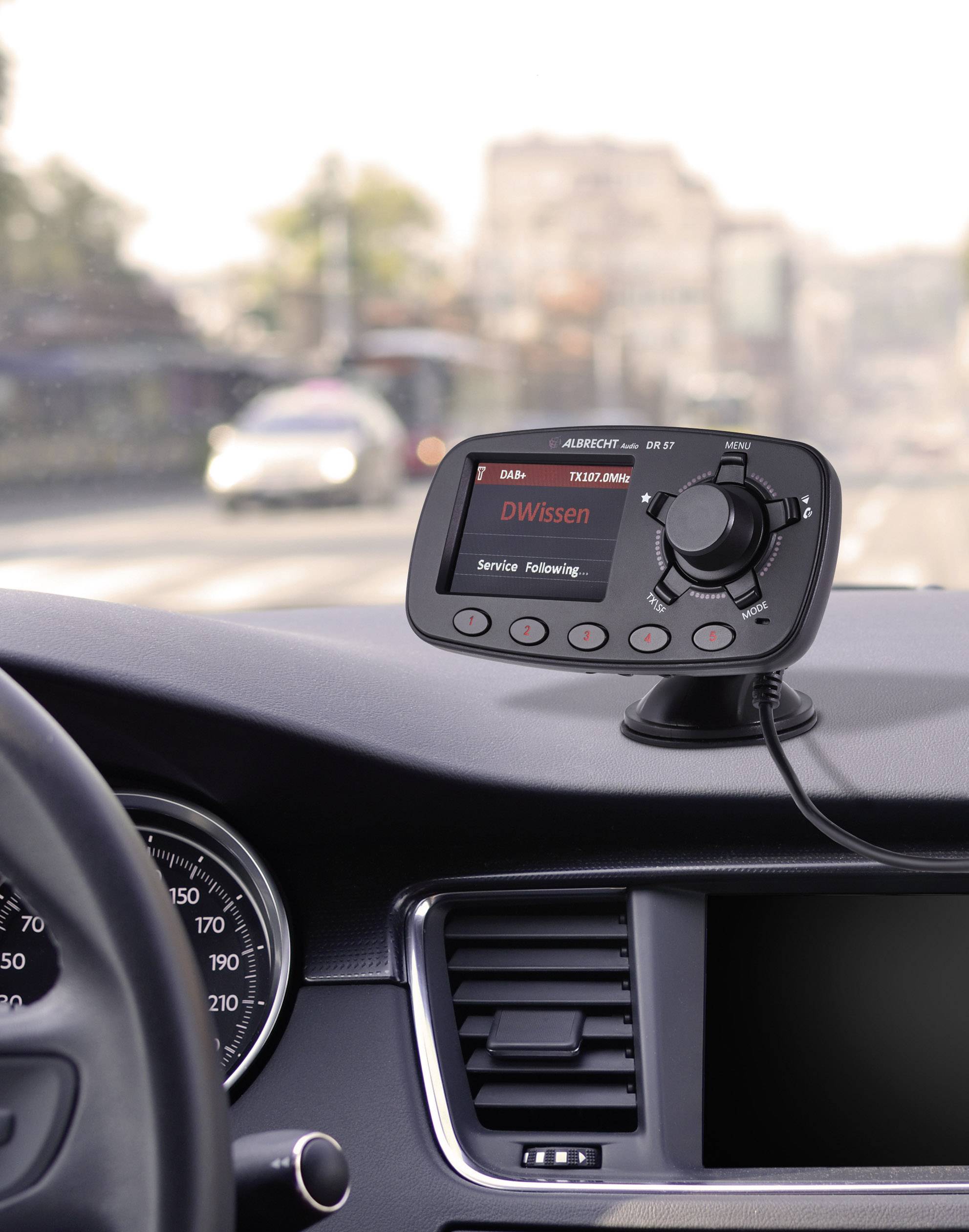 Ein Autoradio-Display in einem Auto zeigt 'DWissen' an. Das Auto fährt auf einer städtischen Straße.