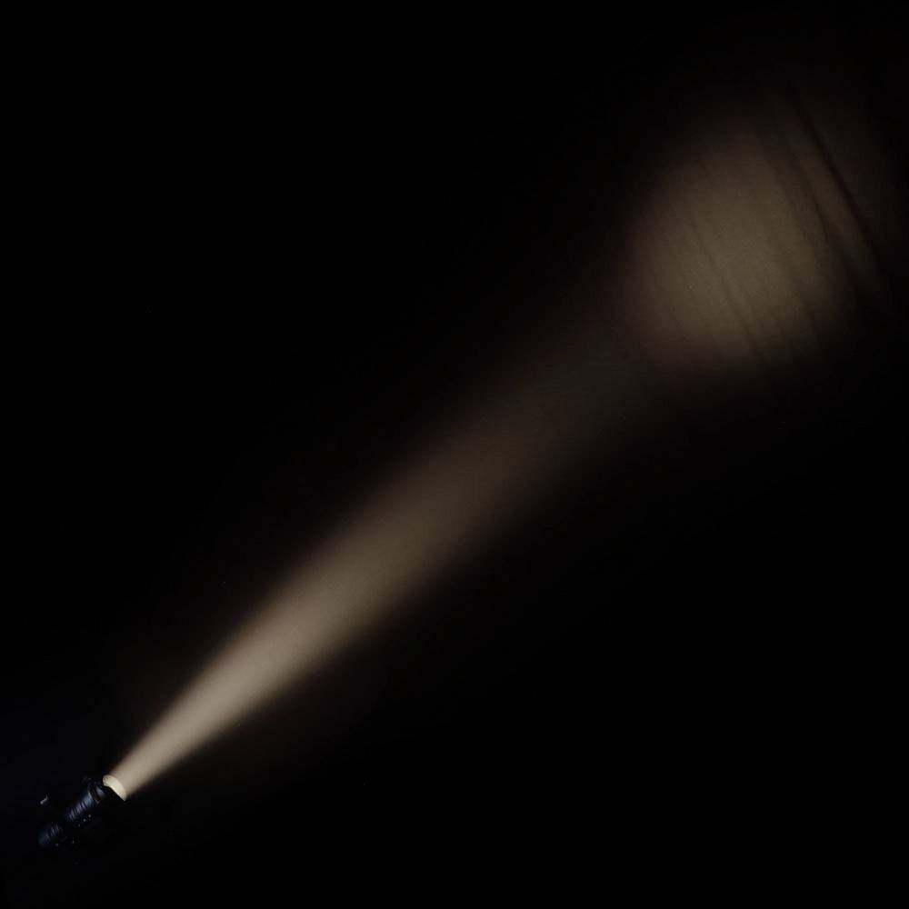 Eine Taschenlampe strahlt einen Lichtkegel in die Dunkelheit, der allmählich schwächer wird.