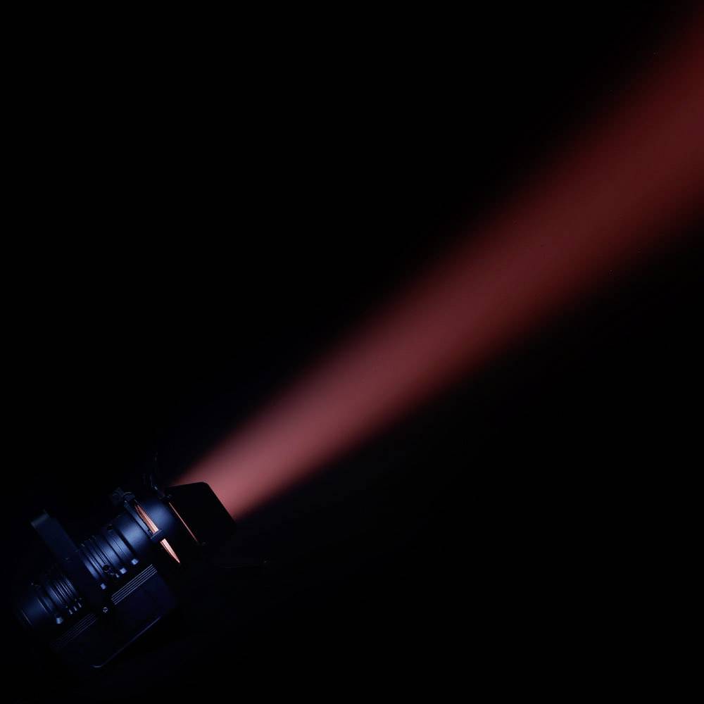 Ein Scheinwerfer projiziert einen leuchtend roten Lichtstrahl in die Dunkelheit, der auf einer Seite des Bildes beginnt.