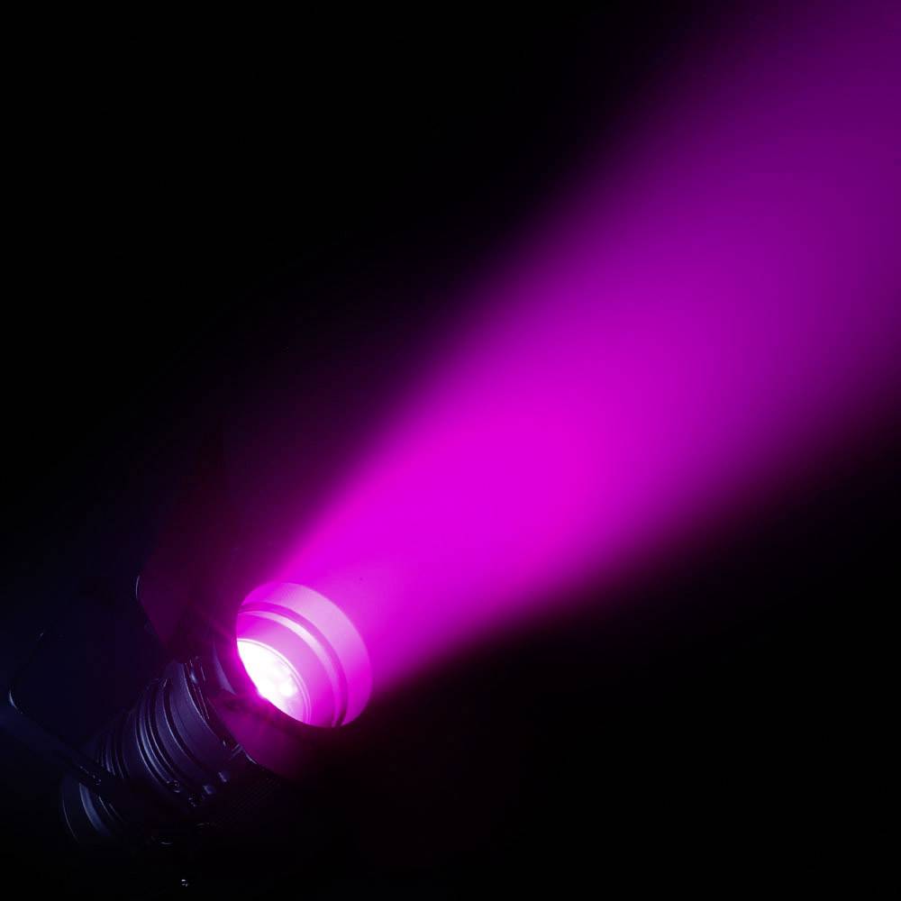 Ein Scheinwerfer projiziert einen kräftigen, pinken Lichtstrahl in die Dunkelheit.