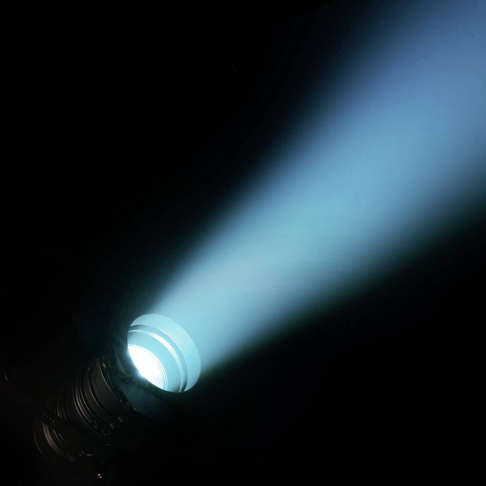 Ein Scheinwerfer strahlt einen blauen Lichtstrahl in einen dunklen Raum.