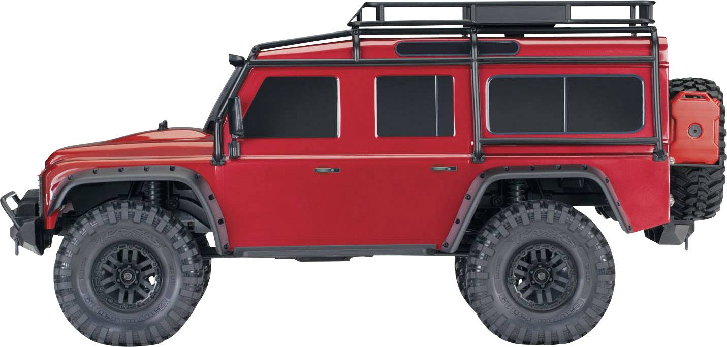 Ein roter Geländewagen mit großen Reifen, auf einem weißen Hintergrund. Der Wagen hat seitliche Stangen und eine Dachreling.