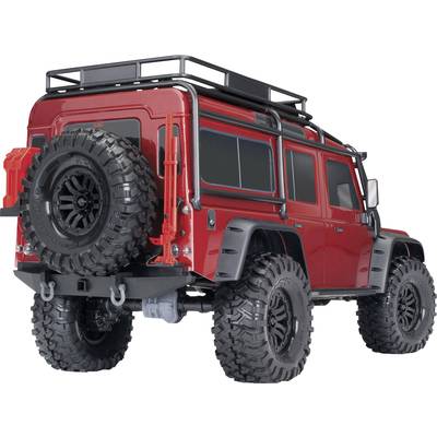 Ein rotes Geländewagen-Modellauto mit großen Offroad-Reifen, Reserverad und Dachträger, aus der Rückansicht fotografiert.