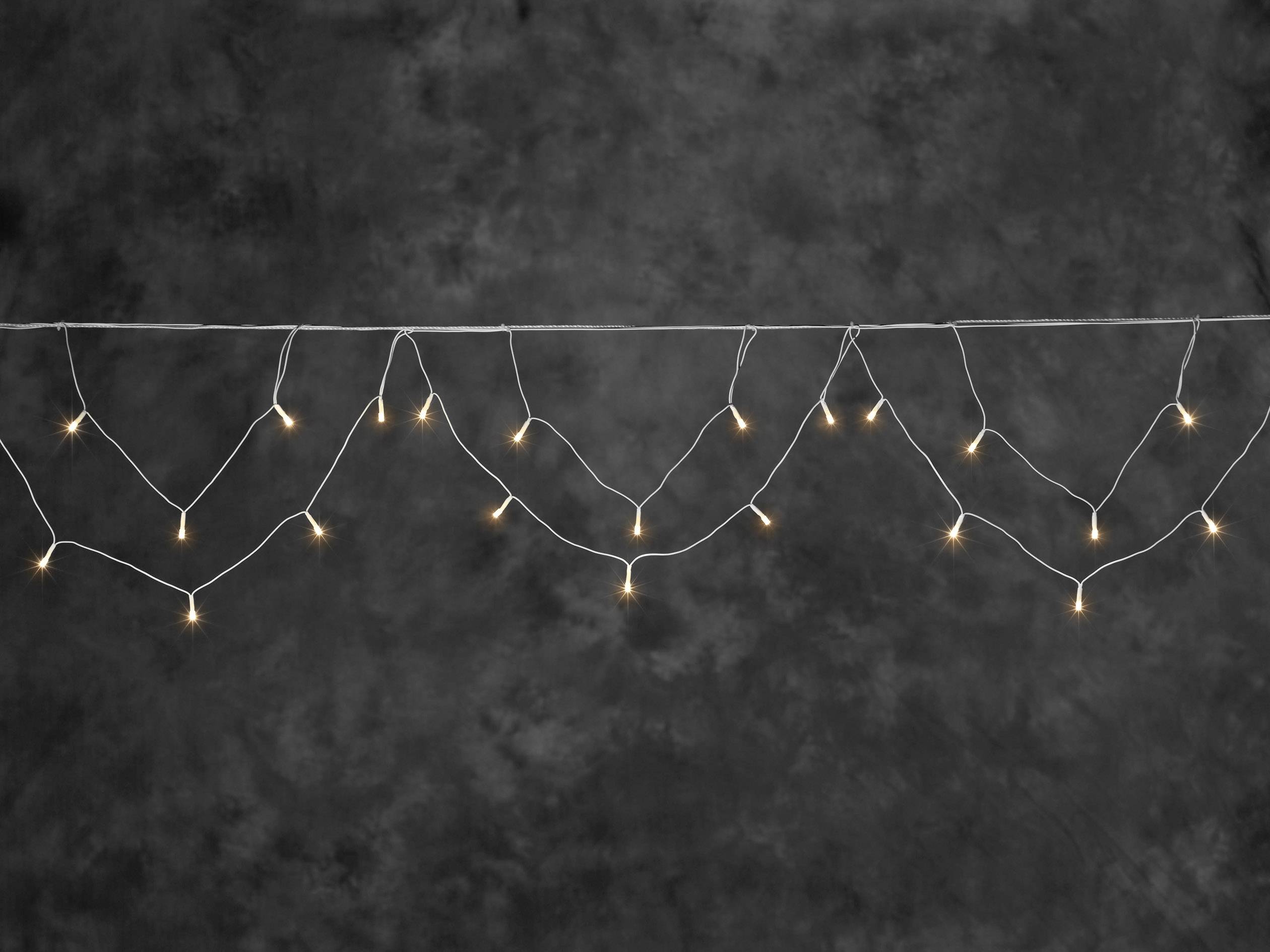 Lichterkette mit kleinen weißen Lichtern vor dunklem Hintergrund.