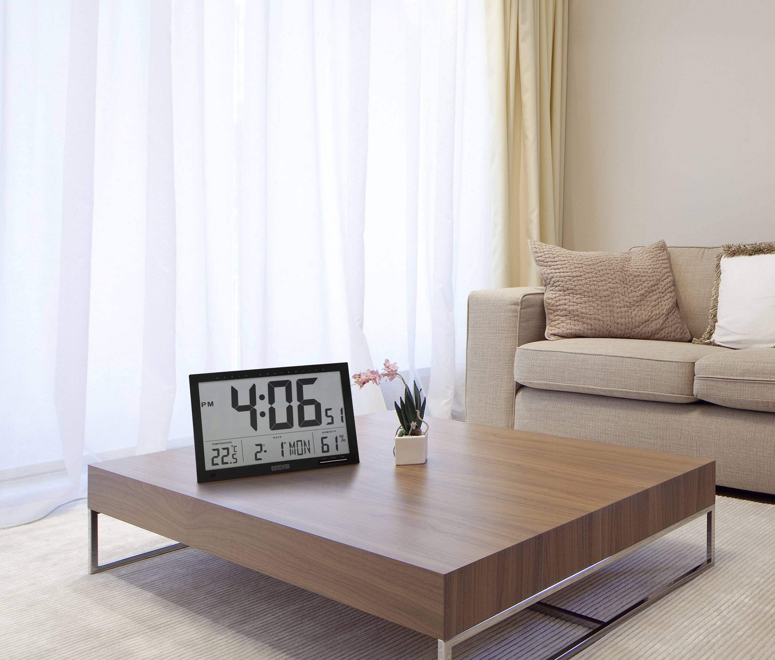 Eine moderne, minimalistische Wohnzimmeransicht mit einem Couchtisch, auf dem eine digitale Uhr '4:06 PM' anzeigt, befindet.
