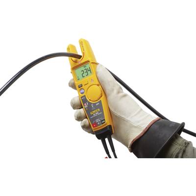 Eine Hand in einem Gummihandschuh hält ein oranges digitales Multimeter, das 234 Volt anzeigt.
