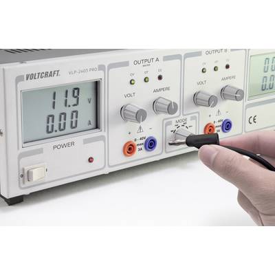 Stromversorgungsgerät mit zwei digitalen Anzeigen für Spannung und Stromstärke. Eine Hand hält eine Prüfspitze, die nahe einem Anschluss ist.