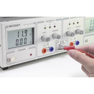 Eine Person misst die Spannung an einem Netzgerät, das 11,9 Volt anzeigt. Das Gerät hat Einstellknöpfe für Spannung und Strom.