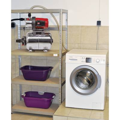 Eine weiße Waschmaschine steht neben einem Metallregal, auf dem sich eine Pumpe und zwei lila Wäscheschalen befinden.