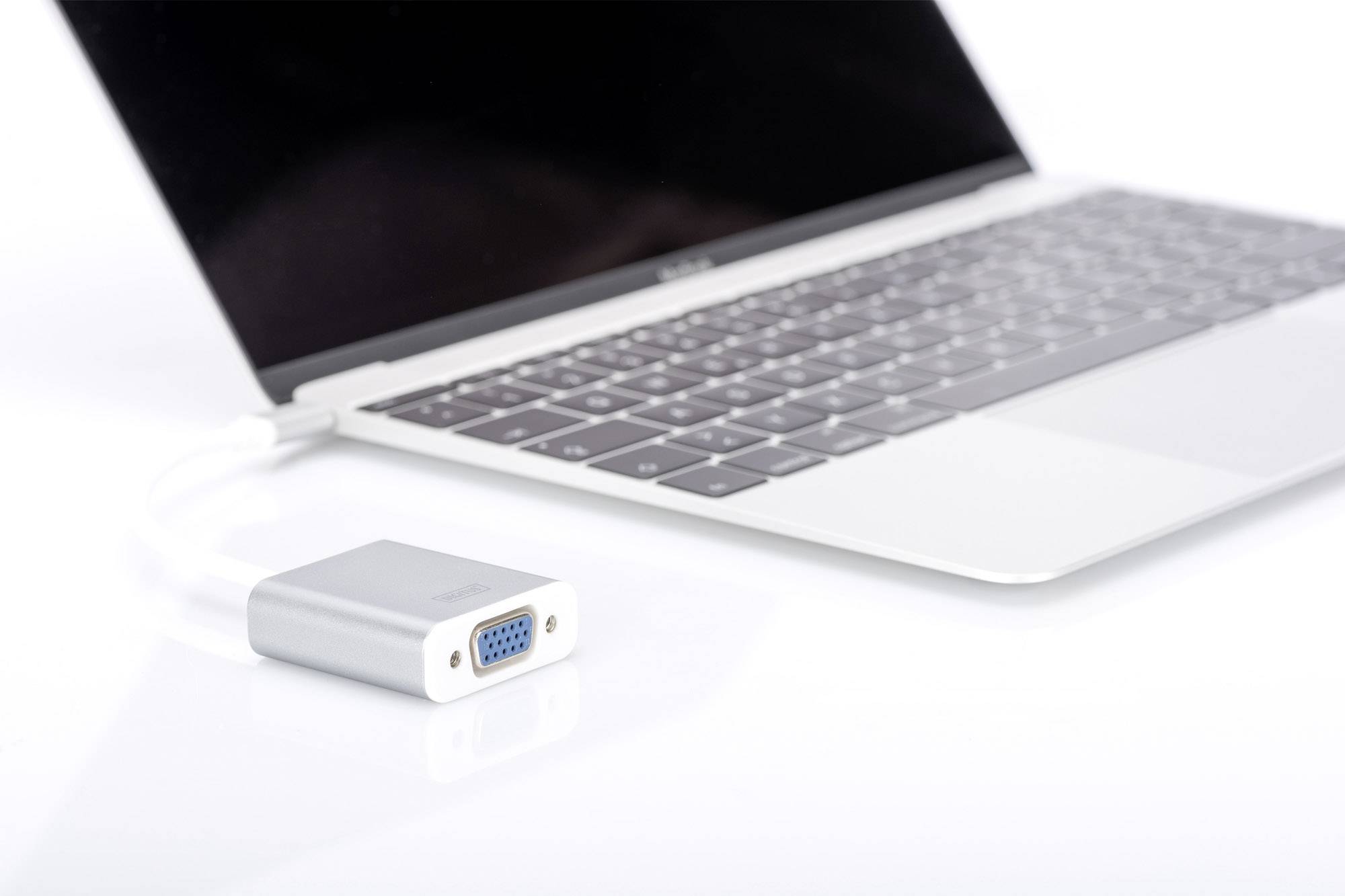 Ein silberner Laptop mit schwarzem Bildschirm, daneben ein VGA-Adapter. Der Adapter ist neben der Tastatur positioniert.