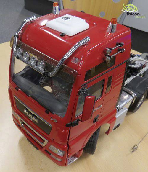 Roter Spielzeug-LKW im Maßstab mit detaillierten Merkmalen, auf einem Tisch stehend. Modell als dekoratives Element platziert.