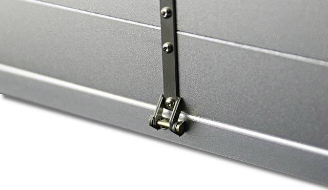 Nahaufnahme eines Metallverschlusses an einer silbernen Oberfläche, möglicherweise ein Teil eines Koffers oder Geräts.