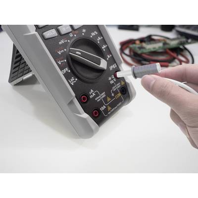 Ein Multimeter wird zur Messung verwendet. Eine Hand hält eine Sonde, die in einen Steckplatz des Geräts eingeführt wird.