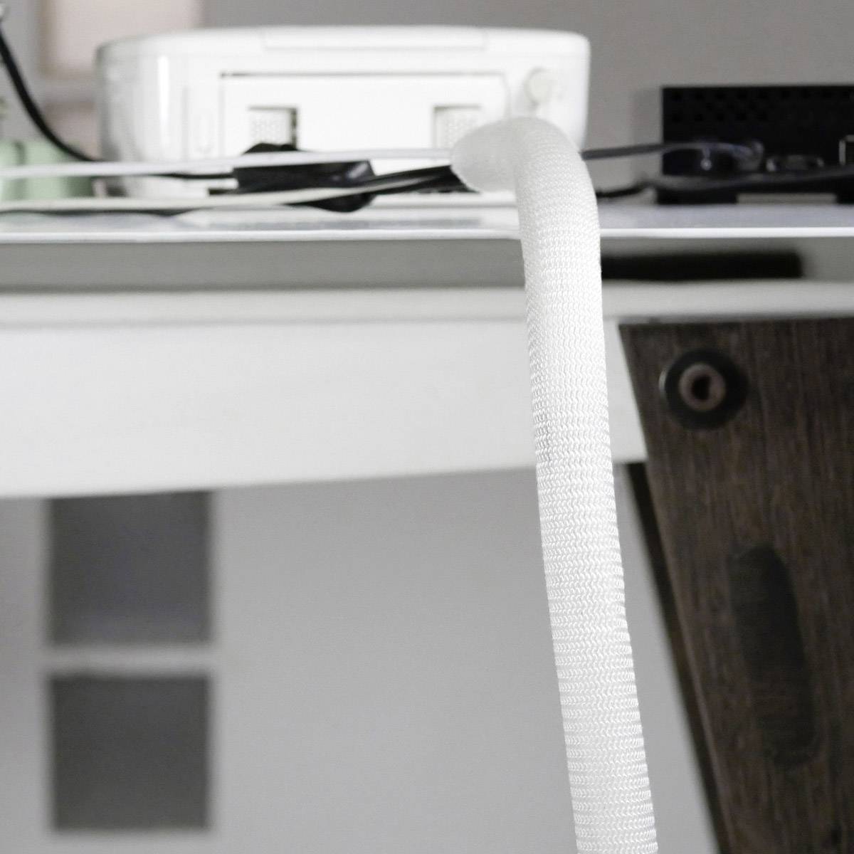 Ein Tisch mit diversen elektronischen Geräten, Kabeln und einem Monitor, zeigt eine typische Arbeitsumgebung im Büro.