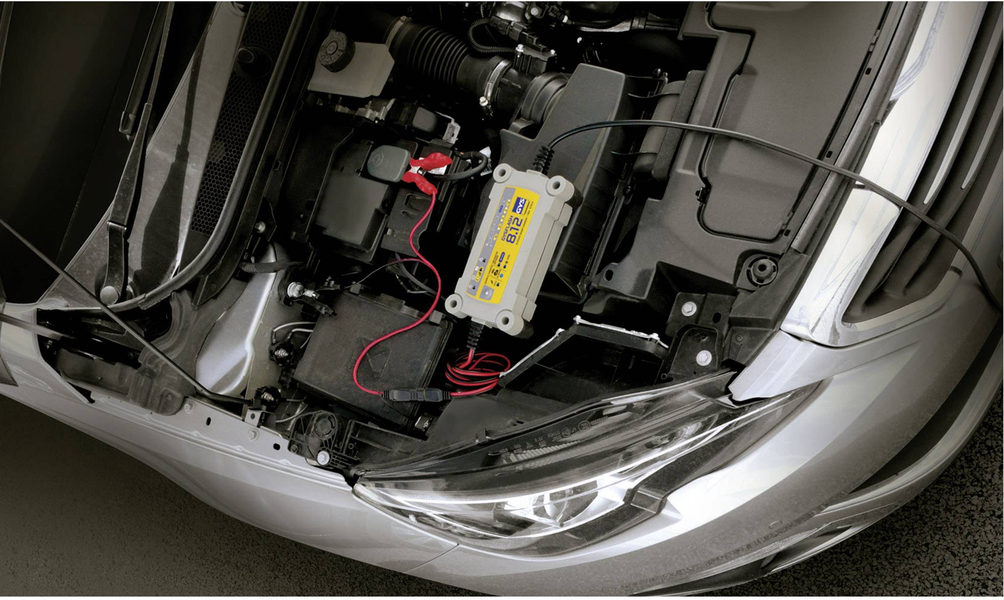 Ein Auto zeigt seinen Motorraum mit einer installierten Batterieladestation, an die eine Autobatterie angeschlossen ist.