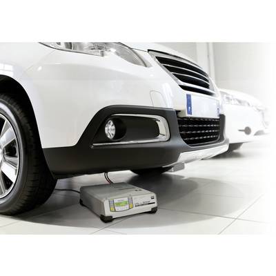 Ein weißes Auto mit einem Batterieladegerät auf dem Boden darunter, das mit dem Fahrzeug verbunden ist. Es steht in einem hellen Raum.