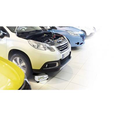 Ein Auto steht mit geöffnetem Motorraum in einer Werkstatt. Ein Gerät ist unter dem Motor platziert, um eine Diagnose durchzuführen.
