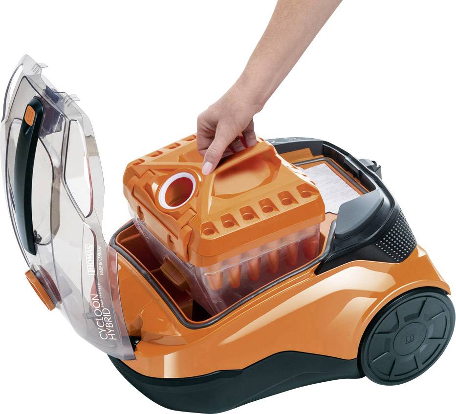 Staubsauger in Orange und Schwarz mit abnehmbarem Behälter, der von einer Hand gehalten wird. Deckel des Staubsaugers ist geöffnet.