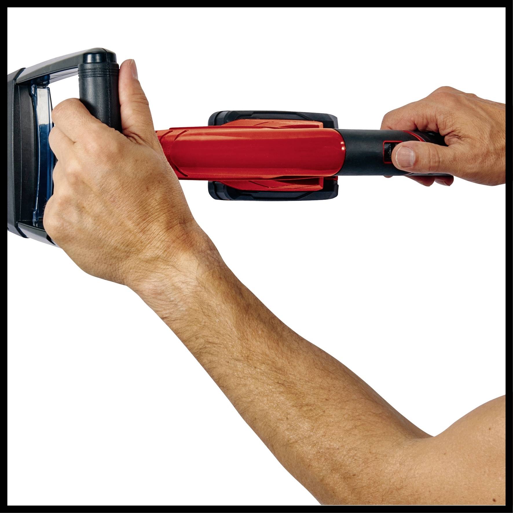 Ein Arm hält eine rote und schwarze Lötlampe, bereit zum Einsatz. Die Hände zeigen den Griff und den Auslöser.