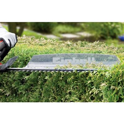 Person schneidet eine grüne Hecke mit einer elektrischen Heckenschere im Garten.