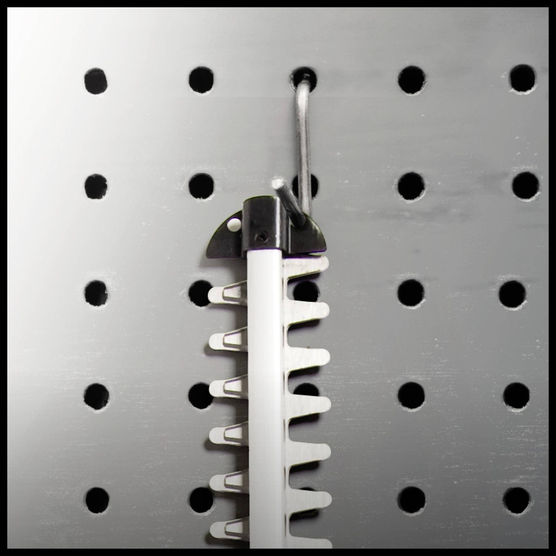 Lochwand mit Haken, an dem ein Werkzeug mit Klingen aufgehängt ist.