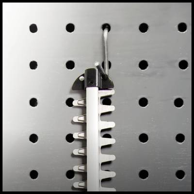 Lochwand mit Haken, an dem ein Werkzeug mit Klingen aufgehängt ist.