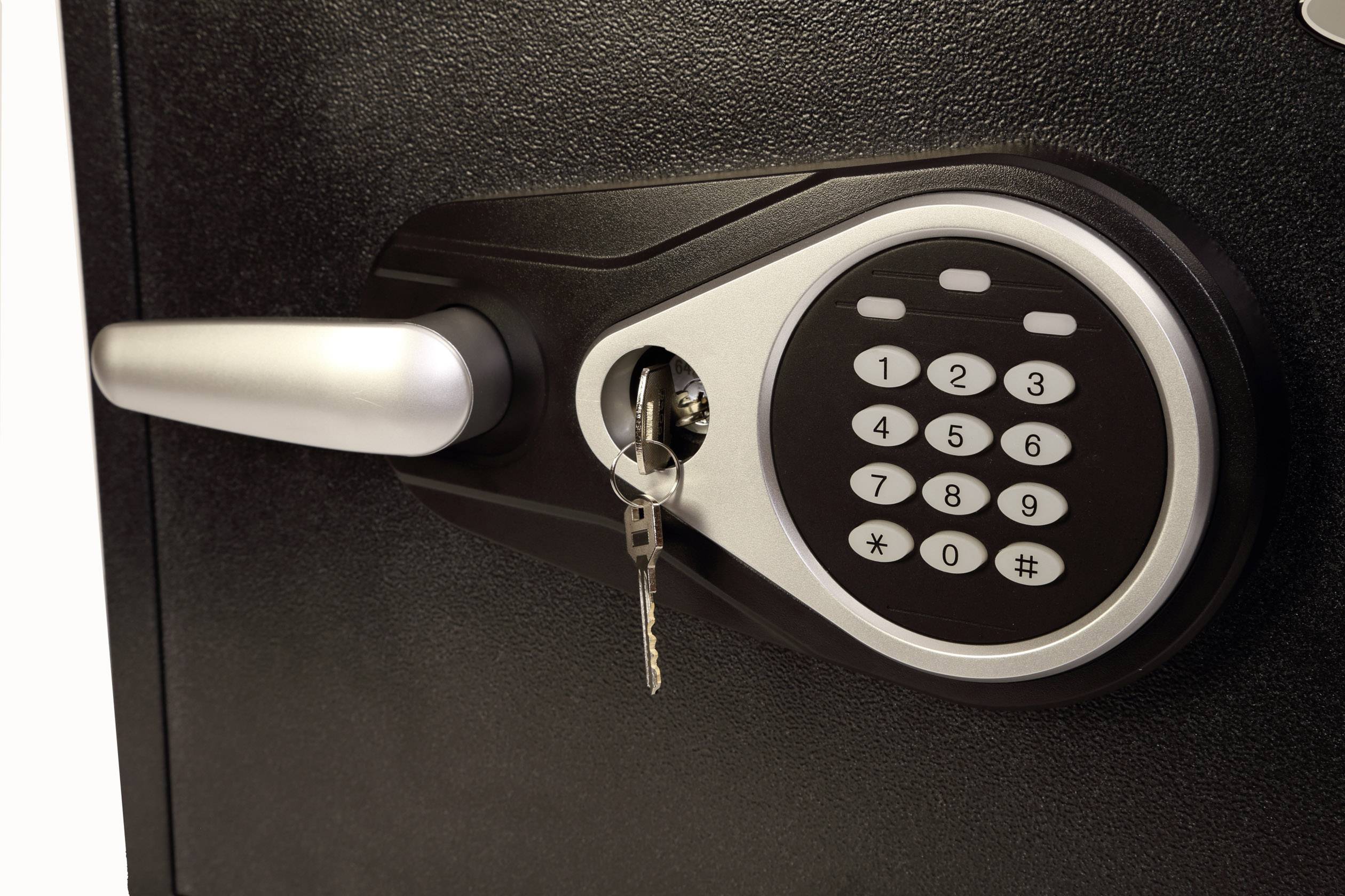 Ein elektronisches Schloss an einem Safe mit Zahlenfeld und einem steckenden Schlüssel links daneben.
