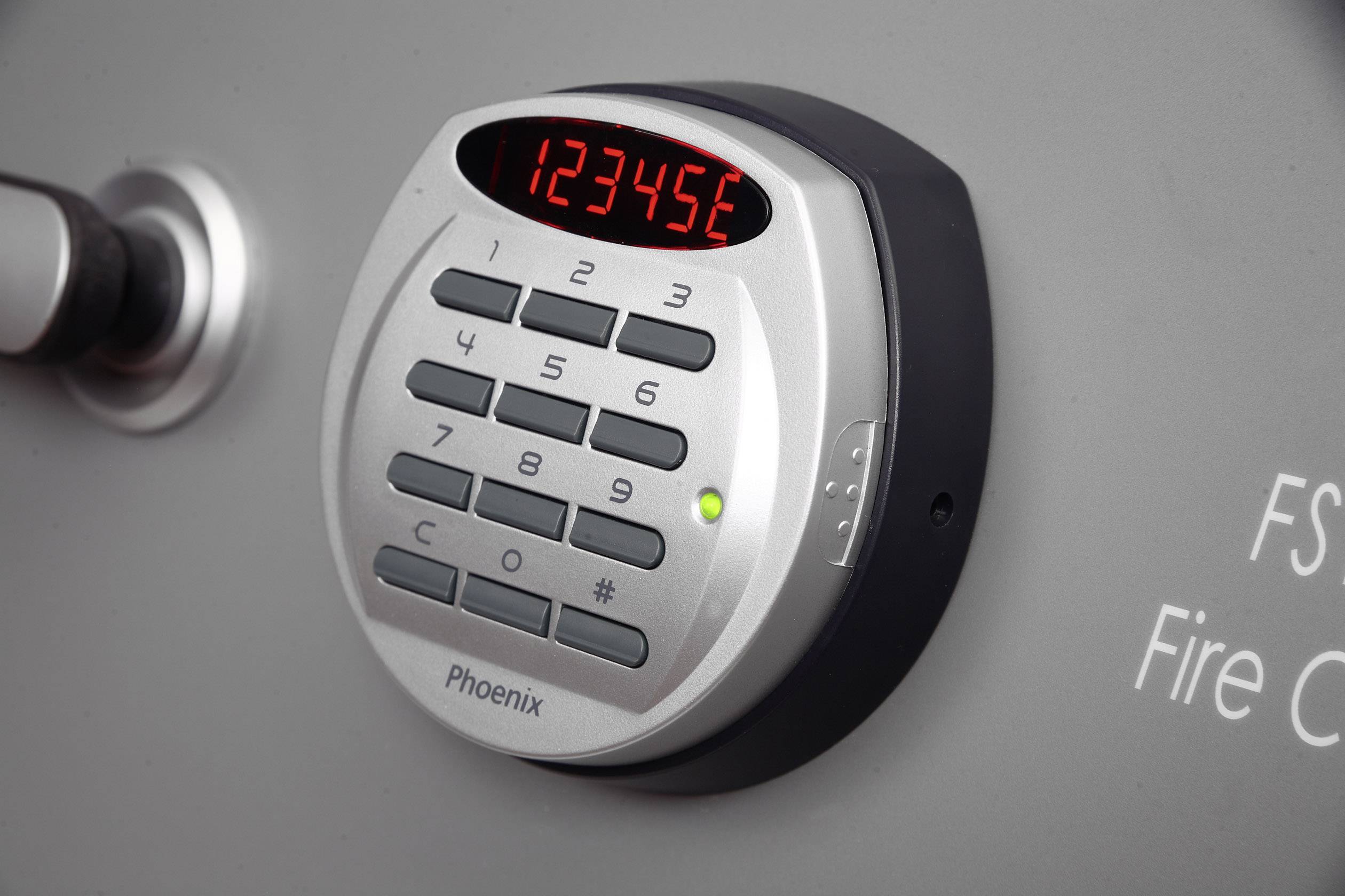 Elektronisches Zahlenschloss mit leuchtendem Display zeigt '123456'. Daneben steht 'FS Fire Control'. Sicherheitssystem.