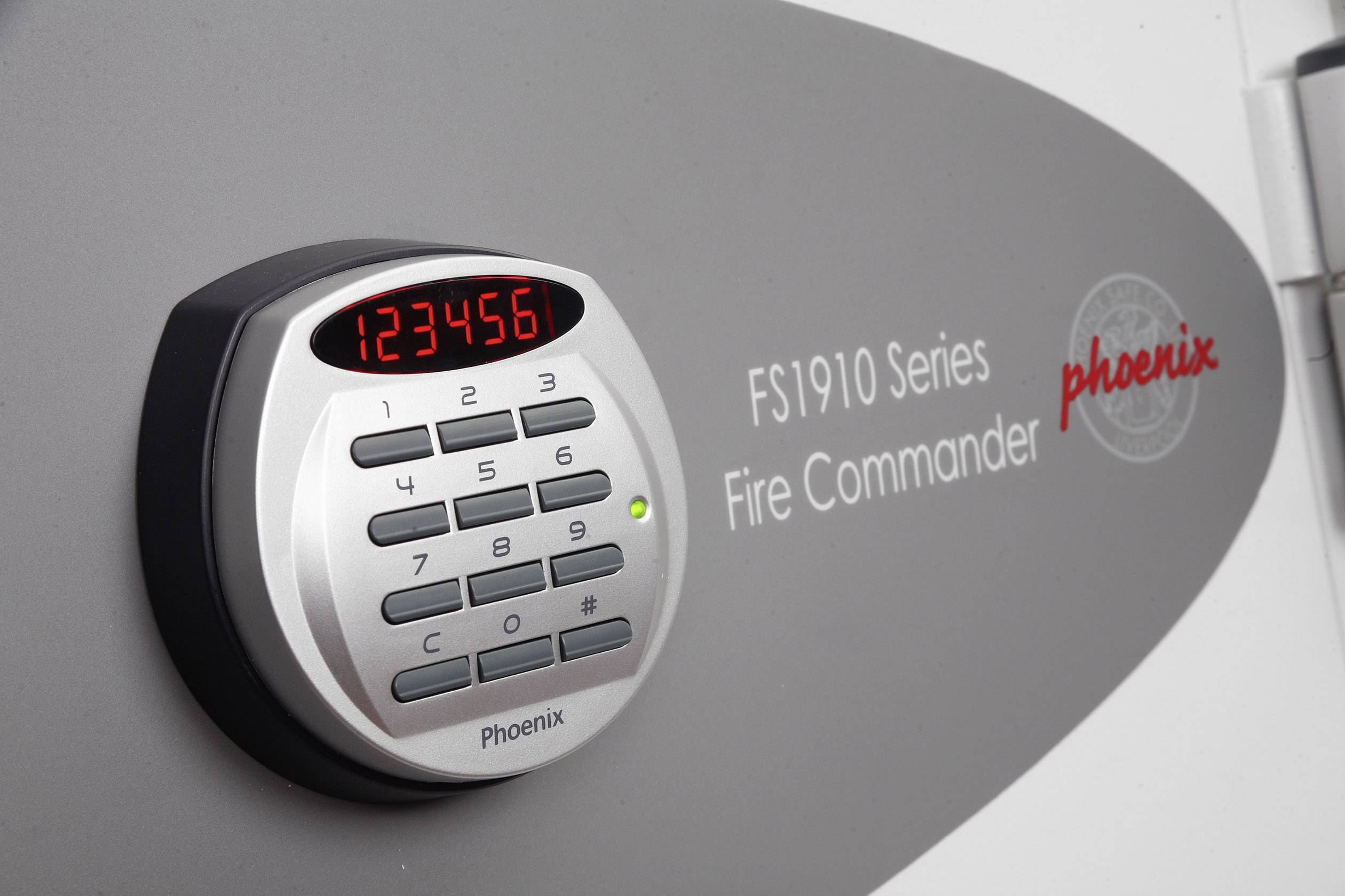 Elektronisches Zahlenschloss eines Tresors mit beleuchtetem Display zeigt '123456'. Aufschrift: 'FS1910 Series Fire Commander - Phoenix'.