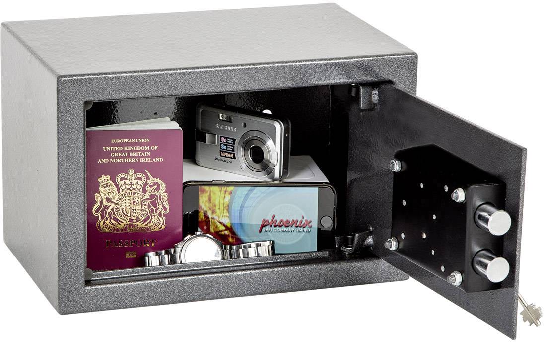 Ein geöffneter Tresor enthält einen Reisepass, eine Kamera und Schmuck, wobei ein Schlüssel im Schloss steckt.