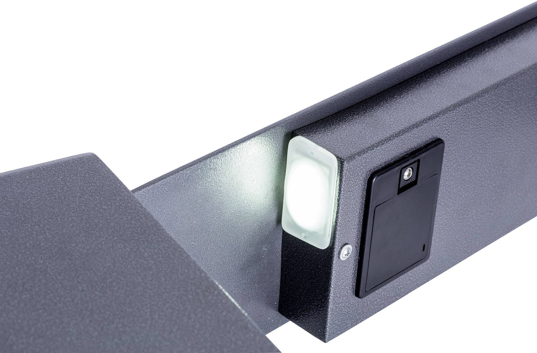 Graues, metallisches Gerätegehäuse mit einem leuchtenden weißen Licht und einem schwarzen rechteckigen Bedienfeld. Beleuchtetes technisches Detail.