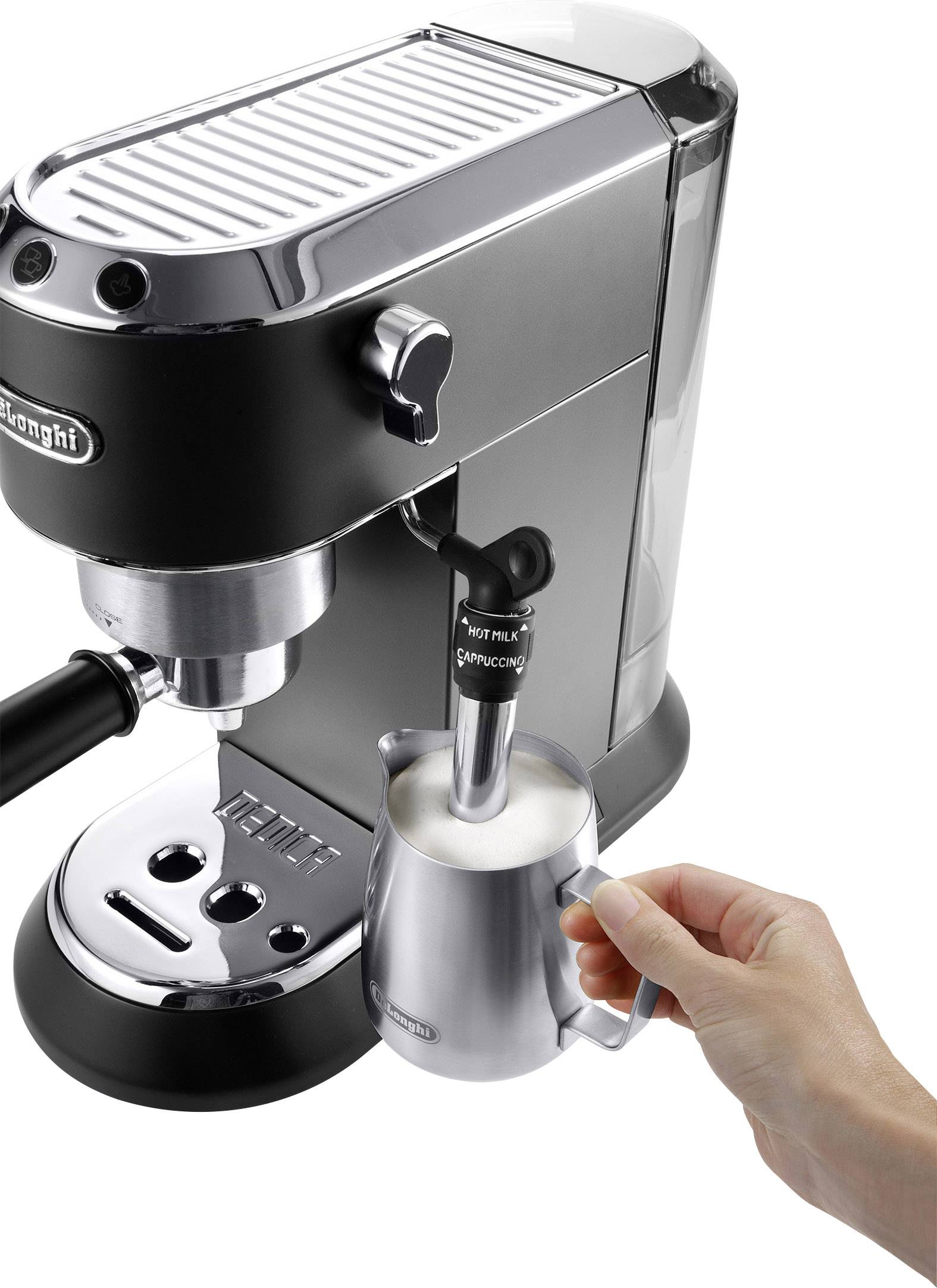 Eine Hand schäumt Milch mit einer silbernen Kaffeemaschine auf.