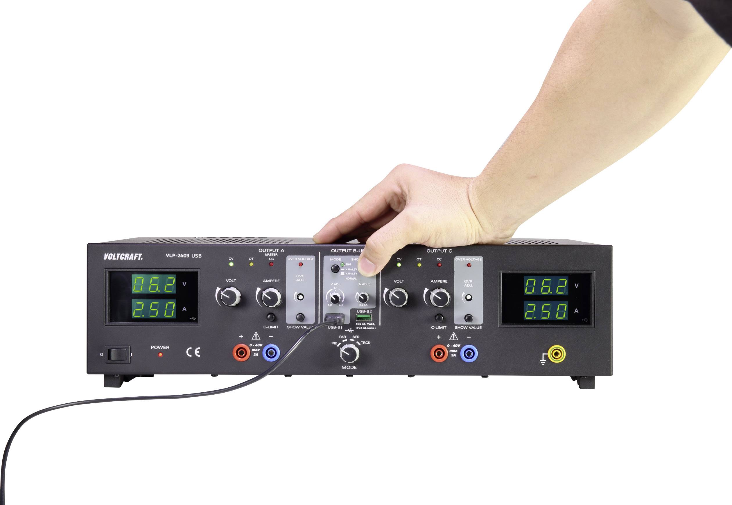 Eine Hand bedient ein schwarzes Netzteil mit Digitalanzeigen und Drehknöpfen. Anzeigen zeigen 0,62 Ampere und 25,0 Volt.