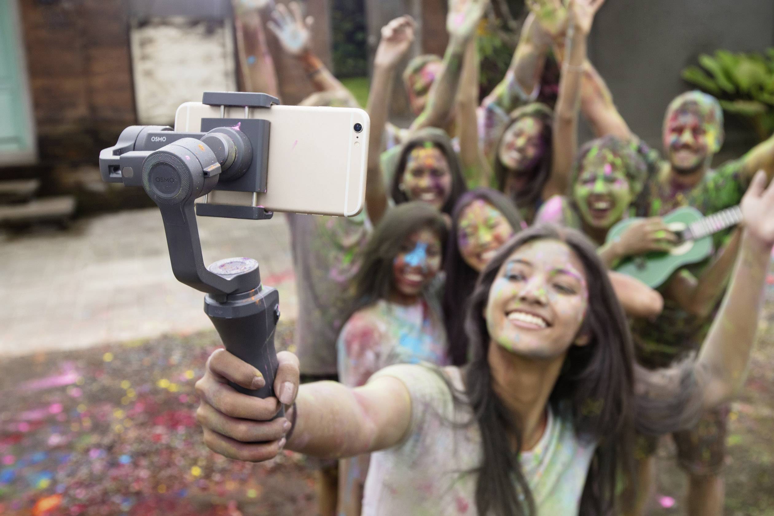Eine Gruppe fröhlicher Menschen macht ein Selfie während eines Holi-Festivals. Ihre Gesichter sind bunt bemalt.