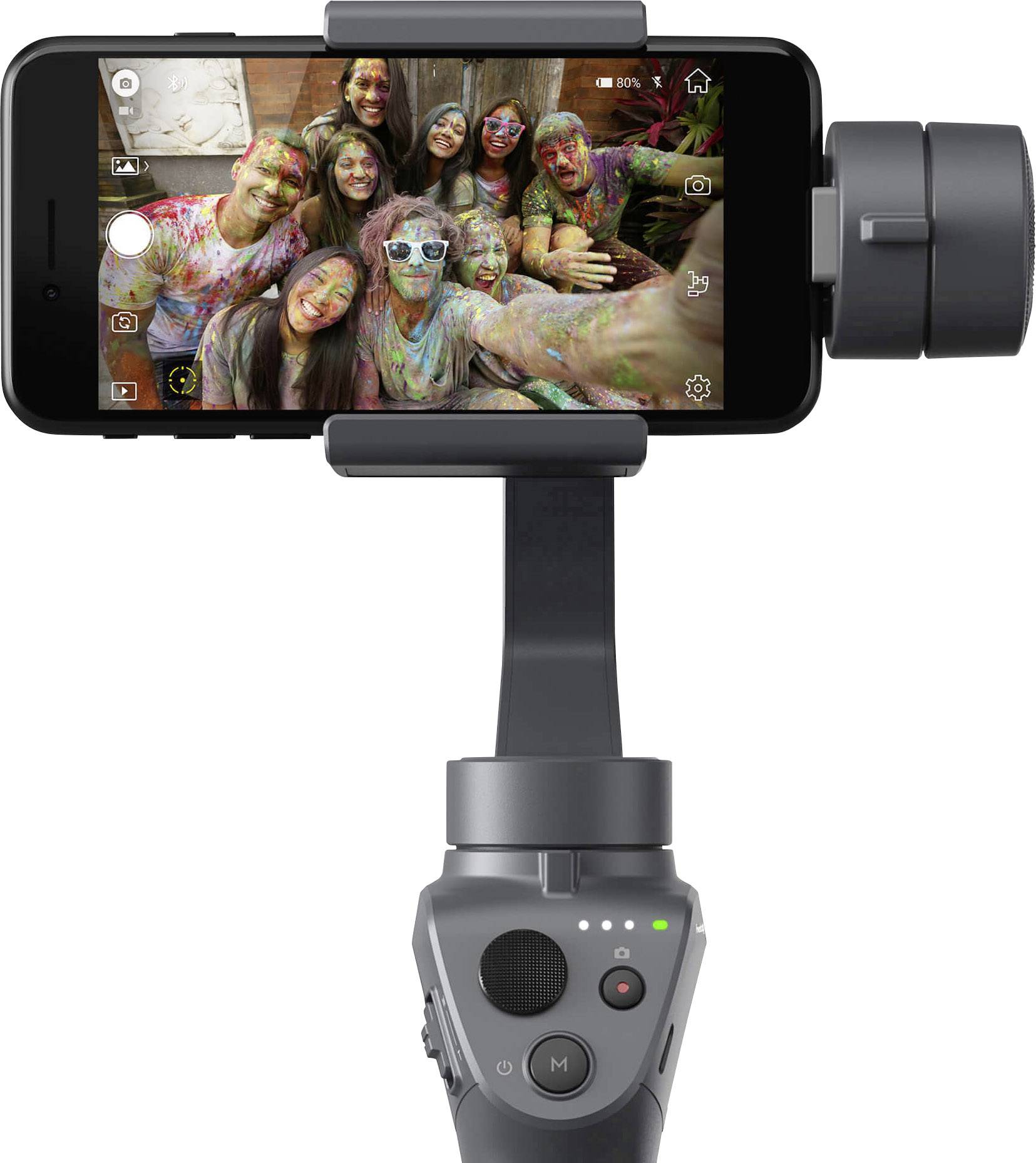 Smartphone auf einem Stabilisator zeigt ein Selfie von sechs fröhlichen Menschen mit buntem Pulver auf Gesichtern und Kleidung.