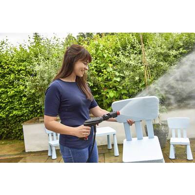 Frau säubert mit einem Hochdruckreiniger einen blauen Holzstuhl im Garten. Im Hintergrund sind weitere Stühle und Pflanzen zu sehen.