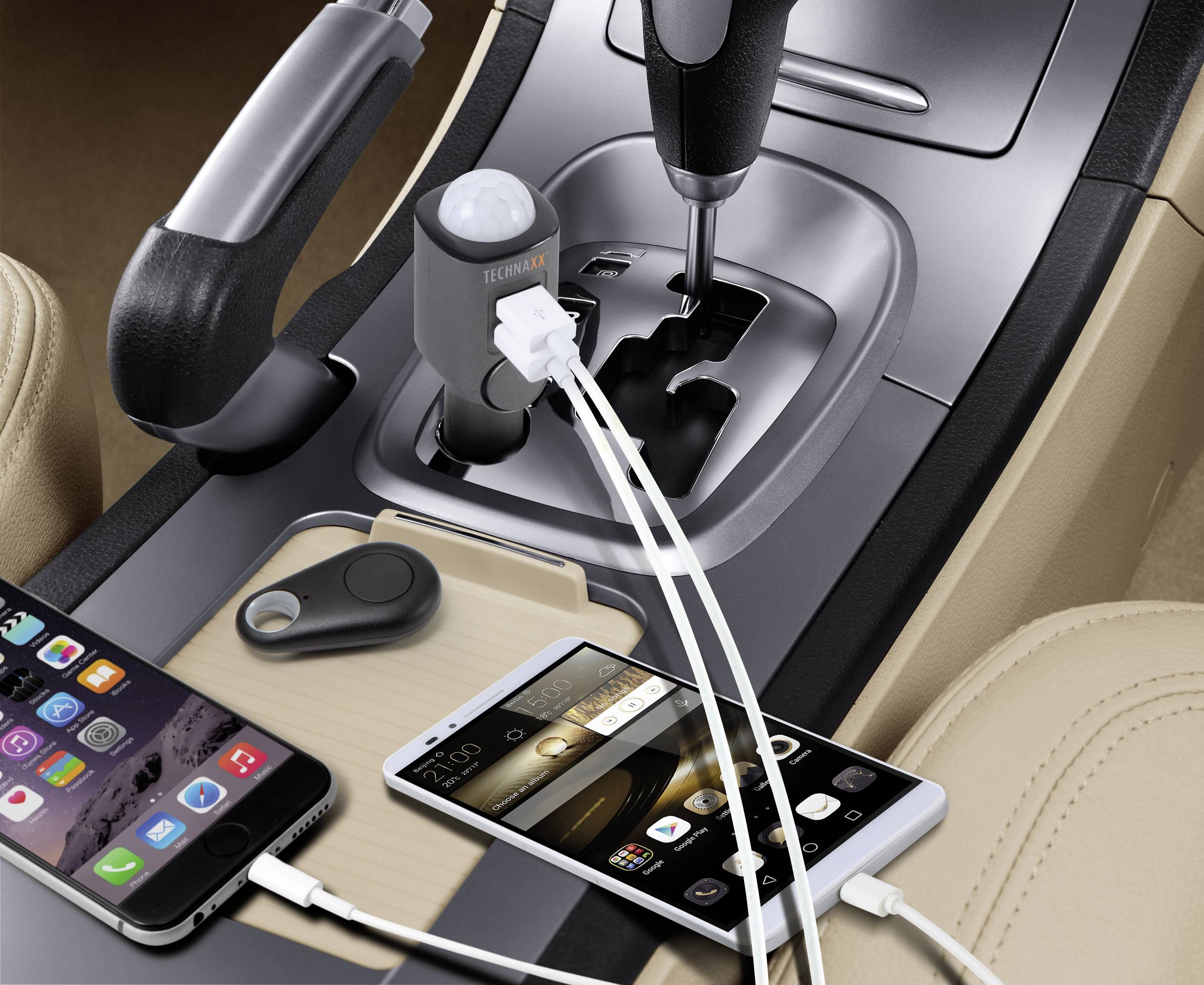 Zwei Smartphones sind an ein Ladegerät im Auto angeschlossen. Ein Schlüsselanhänger liegt daneben, alles auf der Mittelkonsole platziert.