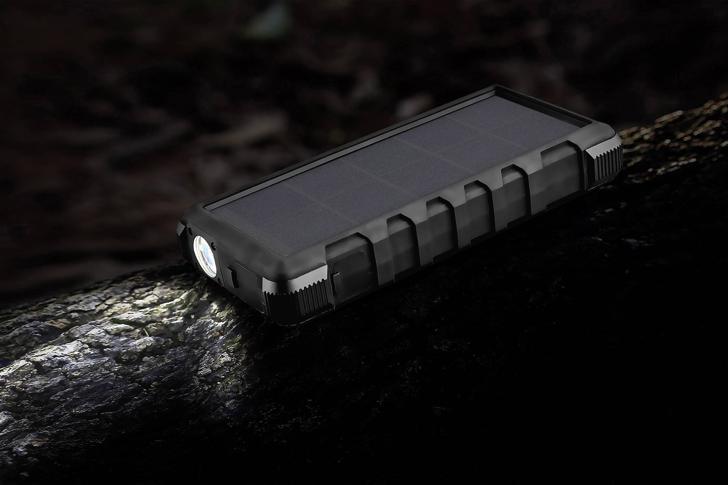 Eine schwarze Solar-Powerbank mit integrierter Taschenlampe liegt auf einem Baumstamm im Dunkeln.