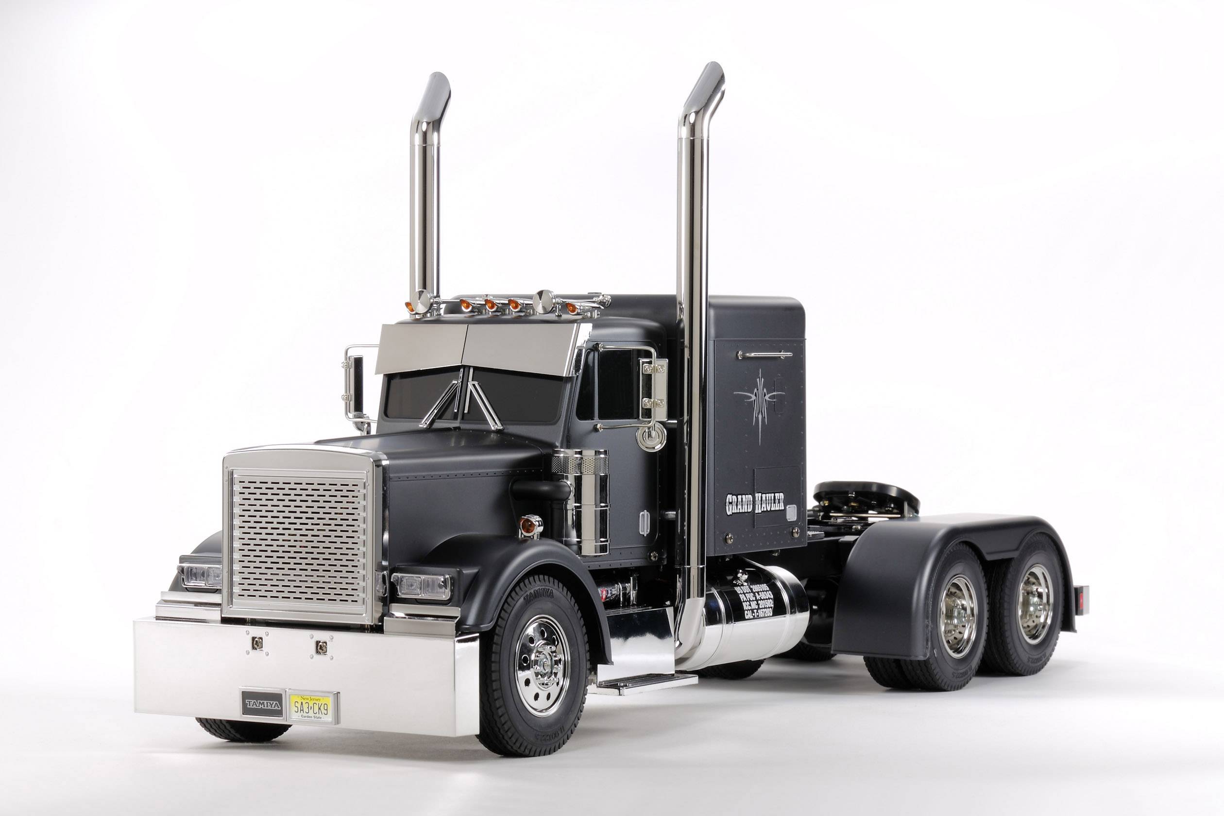 Schwarzer amerikanischer Sattelzug ohne Auflieger, mit großen verchromten Auspuffrohren, steht auf weißem Hintergrund.