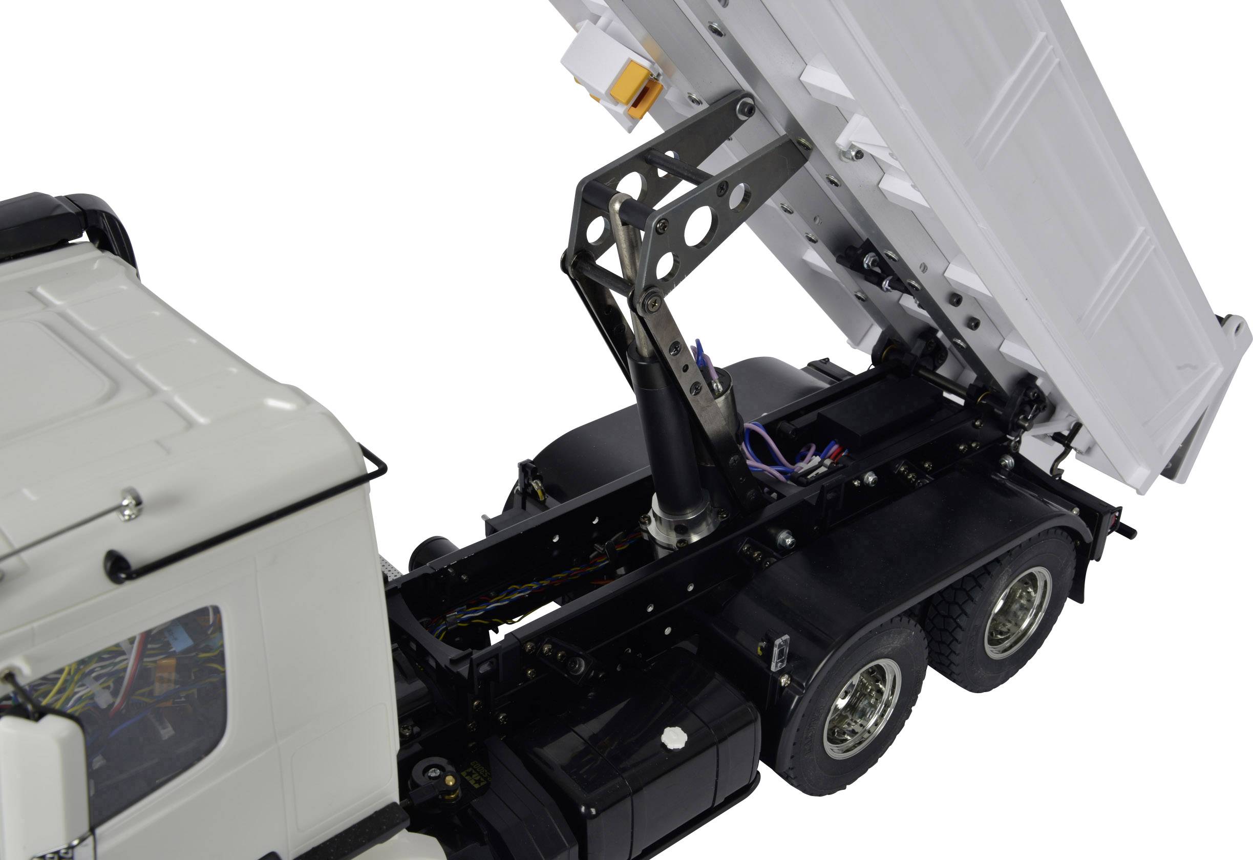 Ein weißer LKW mit einem Kippmechanismus hebt die Ladefläche an. Der Fokus liegt auf dem hydraulischen System am Heck des Fahrzeugs.