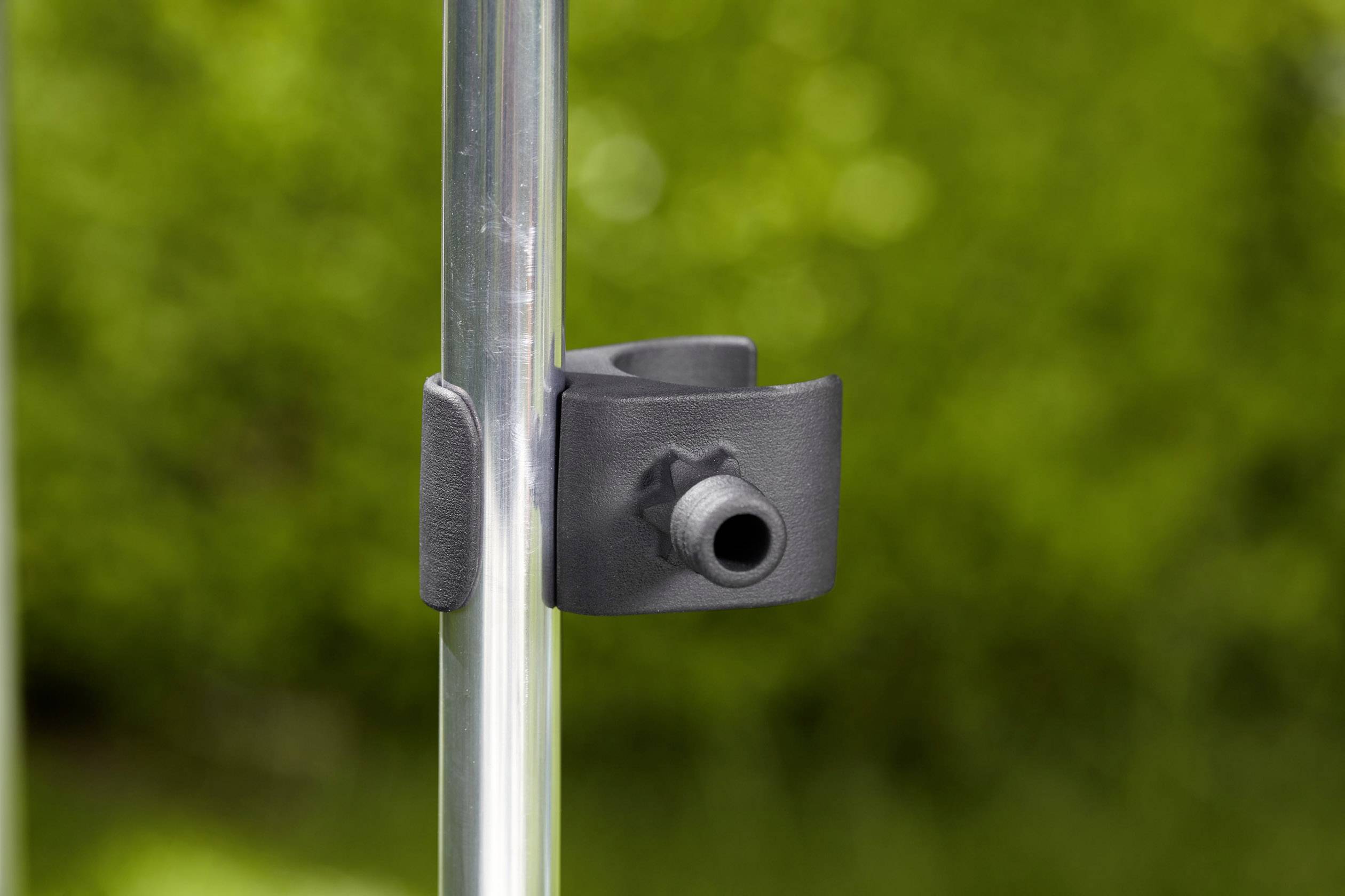 Verschluss an einem silbernen Rohr vor verschwommenem grünen Hintergrund.