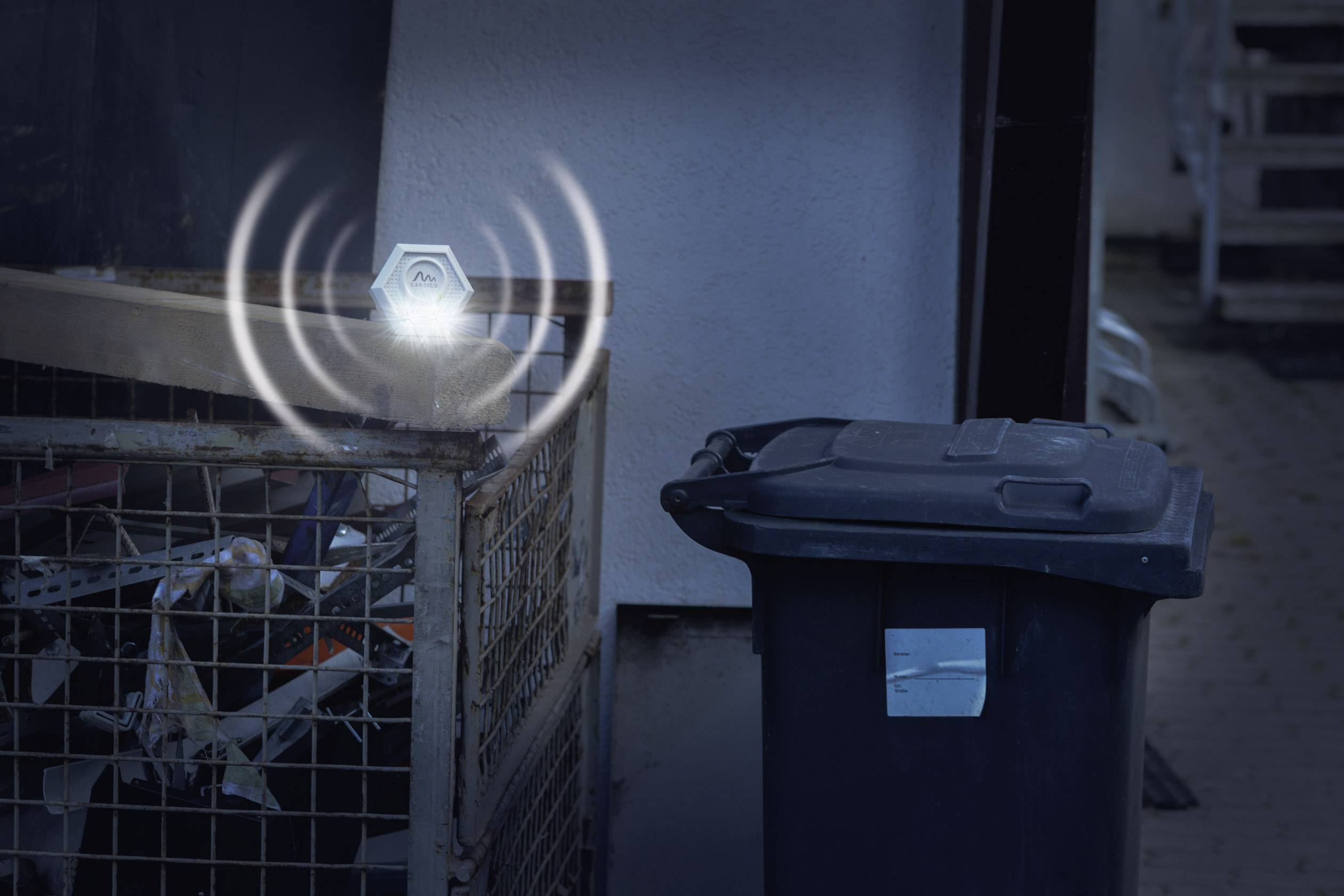 Ein Mülleimer im Freien mit einem Sensor, der Schallwellen abstrahlt. Der Sensor überwacht wahrscheinlich den Füllstand des Behälters.